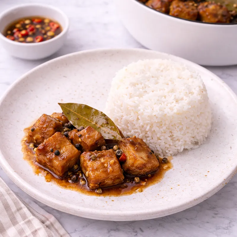 adobong baboy served with white rice and fish sauce with chilies for dipping sauce