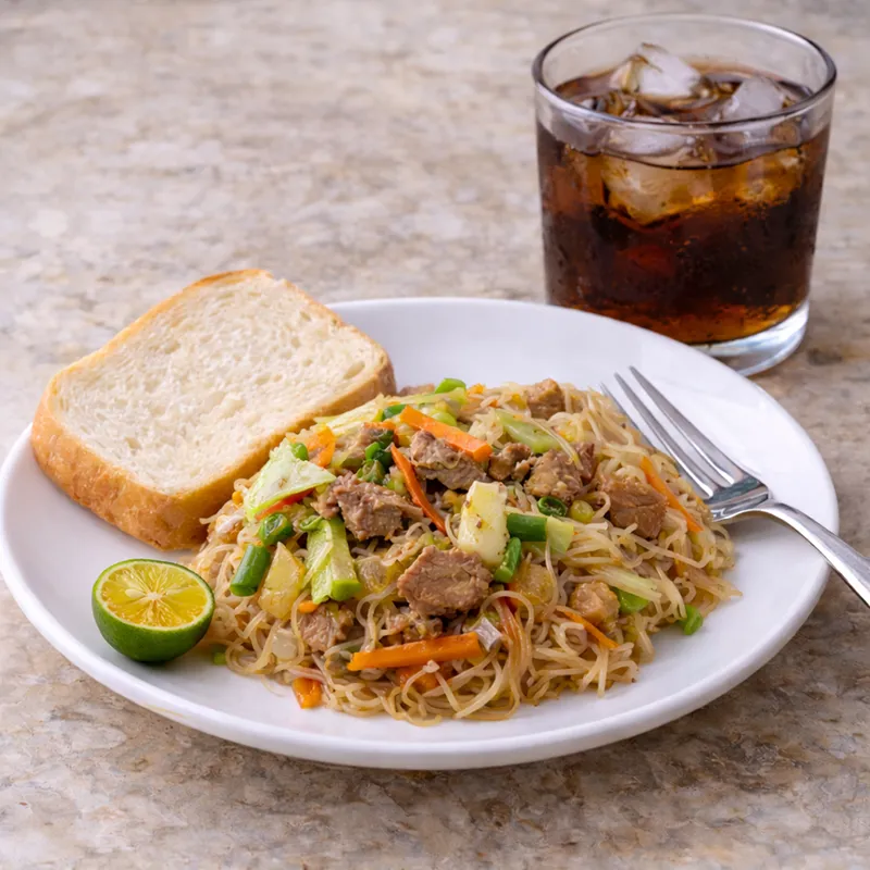family day merienda idea - a plate of pansit guisado with a piece of bread and halve calamansi, with a glass of soda with ice