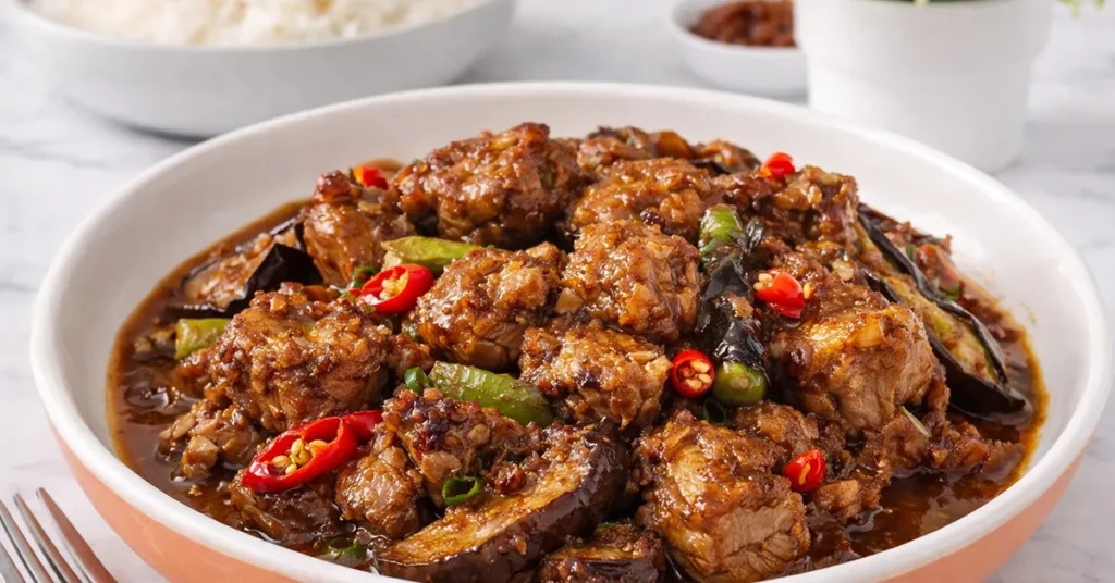 a serving bowl of pork binagoongan with talong