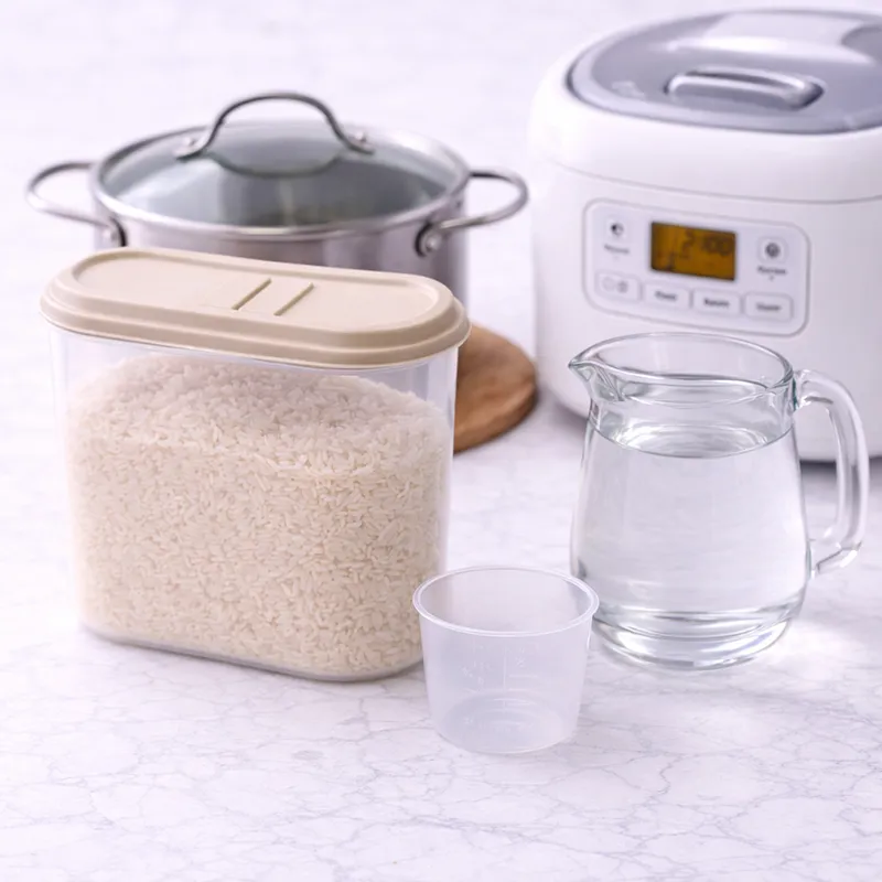 stainless steel pot, rice cooker, rice container, pitcher of water, and a measuring cup on a marble surface to understand kung paano magsaing